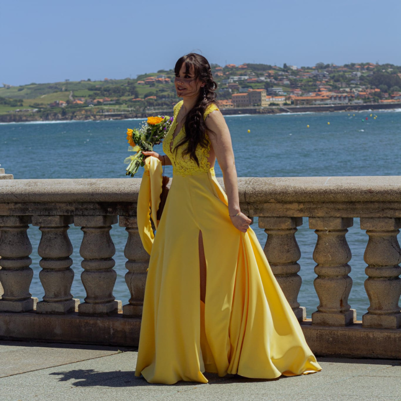 Madrina de boda con vestido amarillo con aperturas en la zona de la pierna y tirantes